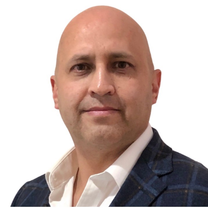 Professional headshot of Fabian de la Fuente wearing a navy plaid blazer and white shirt against a white background.